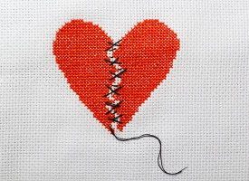 A cross-stitch of a broken heart being stitched back together