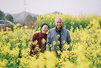 A man and his wife in a healthy relationship standing in a field.