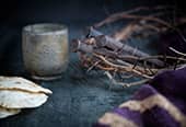 A crown of thorns, rusty nails, a sacrament cup, and some loaves of unleavened bread laying on a table. Symbols of the Savior's Atonement.
