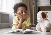 Bored little boy falling asleep while reading a story book.