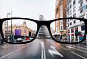 A fuzzy image of a street is made clear through glasses