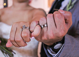 couple holding hands with wedding bands