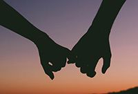 Silhouette of a couple linking pinky fingers.