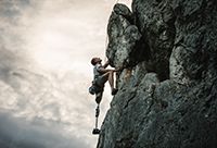 A man with a prosthetic leg climbs a mountain