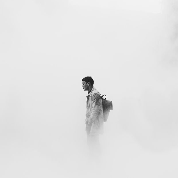 Man standing with his hands in his pockets and surrounded by smoke, signifying the way that passing through adversity can feel like walking in a fog.